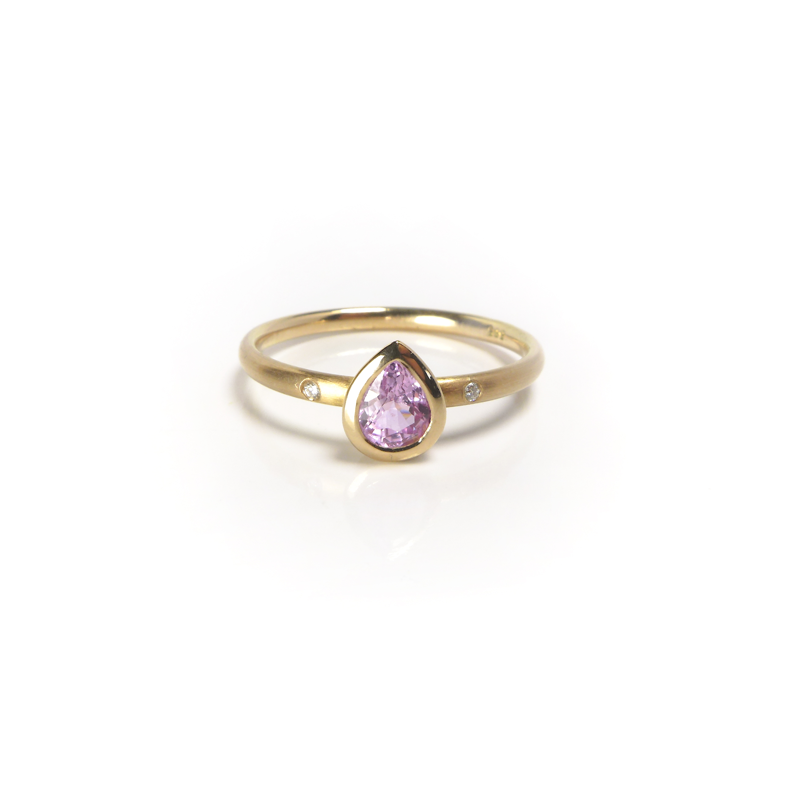 yellow golden ring with a pink tearshaped pink sapphire and two diamonds